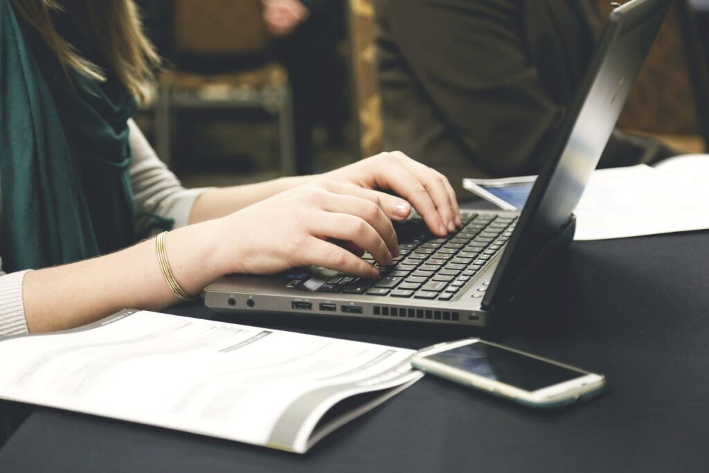 A woman utilizing the Calendly WordPress plugin while typing on a laptop at a conference.